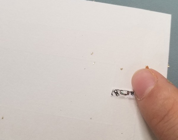 The back of the temporary tattoo backing and metal leaf showing the small LED peeking through. 