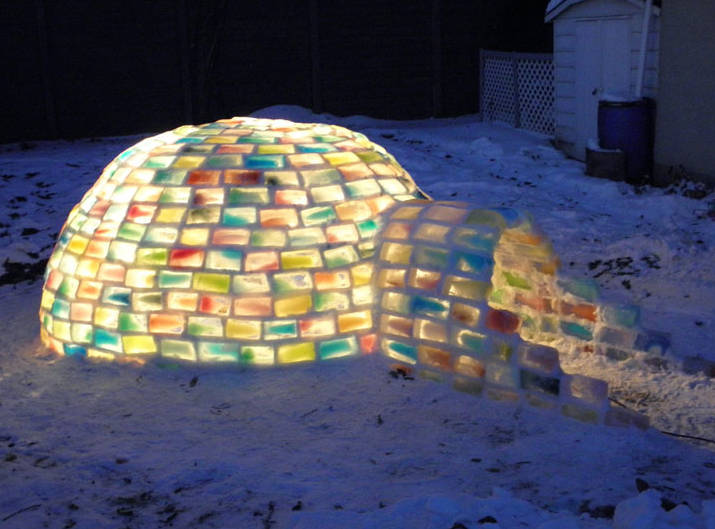 An igloo made from colored ice bricks is illuminated from within