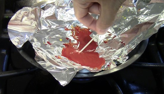 Melted crayons on the stove being stirred with a toothpick.
