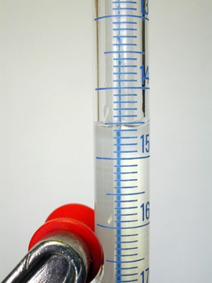 Close up image of the meniscus in a clear fluid within a graduated cylinder