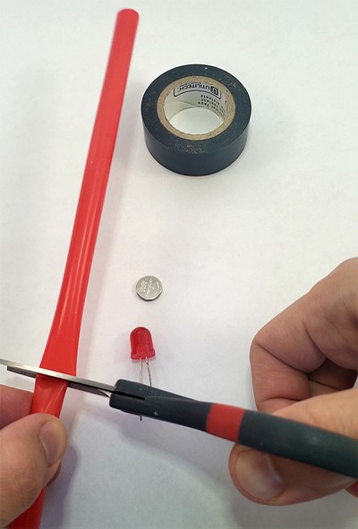 Scissors cutting a straw into two pieces.  
