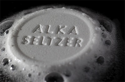 An Alka-Seltzer tablet dissolving and bubbling at the edges