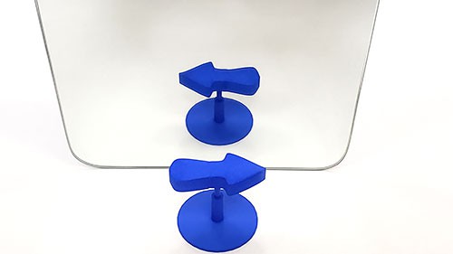 A 3D printed arrow in front of a mirror. The arrow appears to point right, but its reflection appears to point left.  
