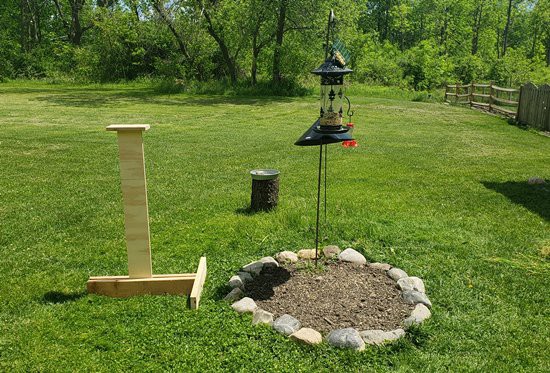  A wooden post next to a bird feeder. 