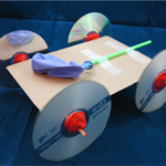 A balloon powered car made from cardboard, tape, CDs, wooden skewers, a straw and a balloon