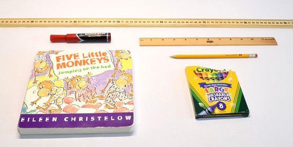 A yardstick, ruler, marker, pencil, book and box of crayons