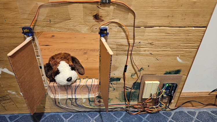 An example of a homemade pet door controlled by an Arduino. A stuffed puppy peeks through the opening.