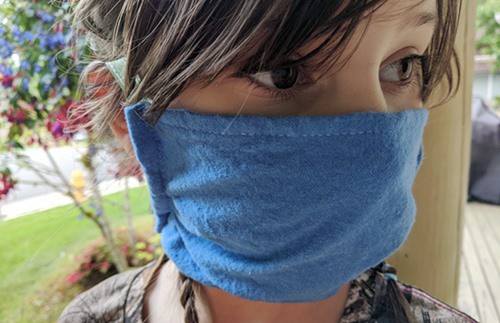 Girl wearing homemade cloth mask with ribbon ties over nose and mouth to protect against COVID-19.