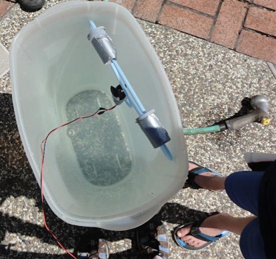 A homemade underwater robot above a plastic bin filled with water