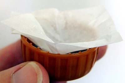 A small sheet of wax paper is pressed into a bottle cap